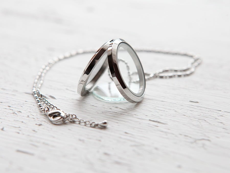 Esta cadena fabricada en oro blanco tiene un colgando con forma de dos anillos unidos y un cristal redondo. El precio es bastante alto, ya que es una joya exclusiva.