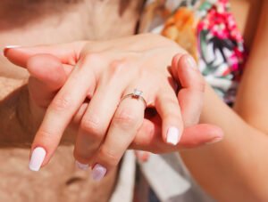 Chica nos muestra el anillo de compromiso que le ha regalado su prometido. Es él quien sujeta la mano para que lo veamos bien.