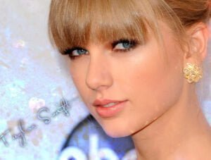 Taylor swift lleva un pendiente de oro muy bonito. Además de ir bien maquillada y estar usando un perfume de sus preferidos.