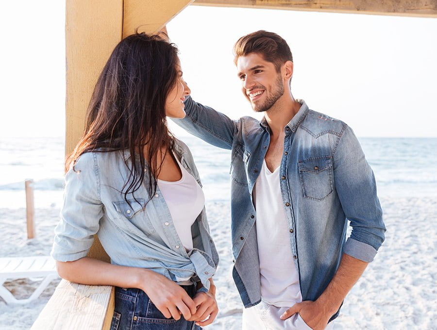 Este hombre está ligando con una chica en la playa. Parece que el perfume que ella lleva le ha atraido y ahora están coqueteando mientras sonríen.