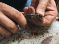 Este maestro orfebre está reparando el cierre de langosta de una cadena de oro de 18 quilates.