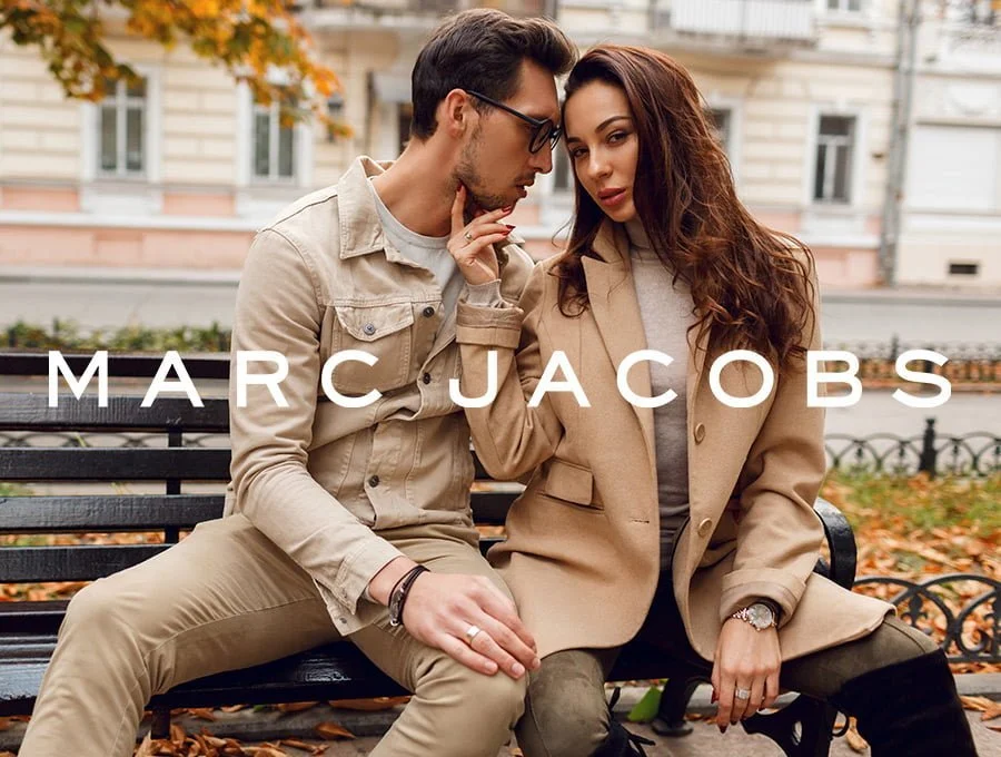 Una pareja disfruta de un encuentro romántico en el parque. Están sentados en un banco de madera. Ella lleva puesto un perfume de Marc Jacobs para épocas frías.