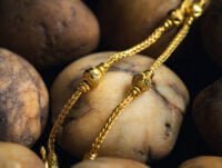 Una cadena de oro de 22 quilates sobre unas piedras redondeadas de río. Es una reliquia familiar de gran valor.