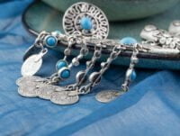 Dentro de esta bandeja o plato de cerámica, hay un collar de plata de ley con monedas decorativas, también tiene algunas piedras decorativas de turquesa.