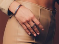 Esta chica lleva un anillo y una pulsera de plata de Tiffany. Lleva además, un pantalón de cuero de color beige.