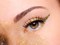 Esta chica lleva brillantina de oro en los ojos. Lleva un maquillaje muy trabajado.