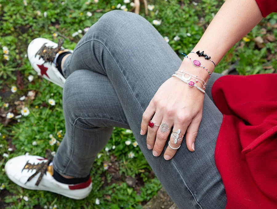 Esta chica está sentada en un rebate del jardín. Lleva puestas varias pulseras de Pandora y algunos anillos de la marca.