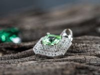 Un colgante con un diamante de color verde y otros más pequeños.