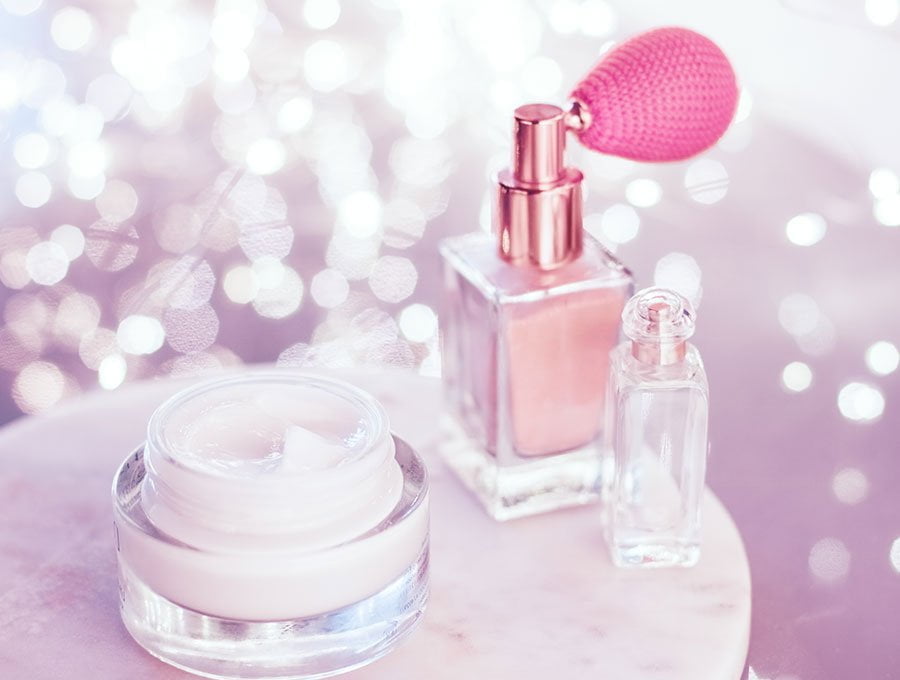 Un frasco de perfume junto a un bote de crema facial de la misma marca.