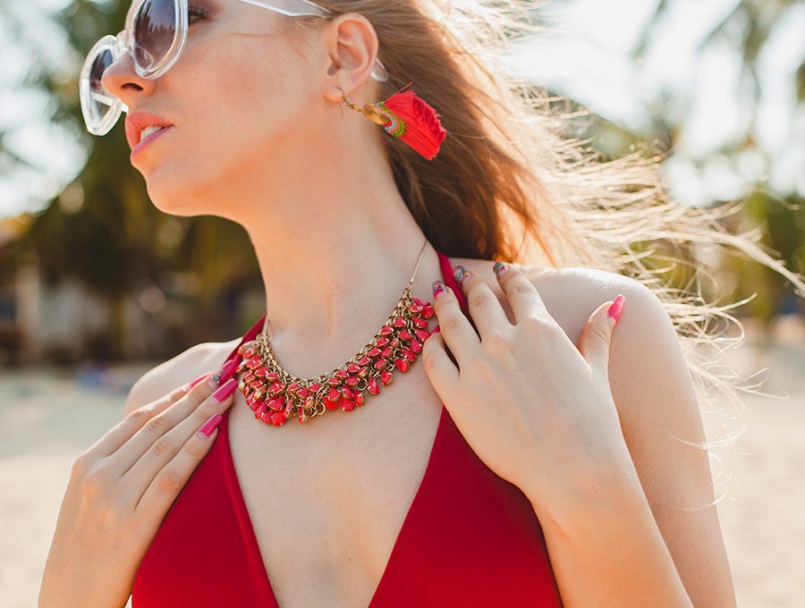 Mujer luciendo un vestido rojo a juego con su collar de perlas.